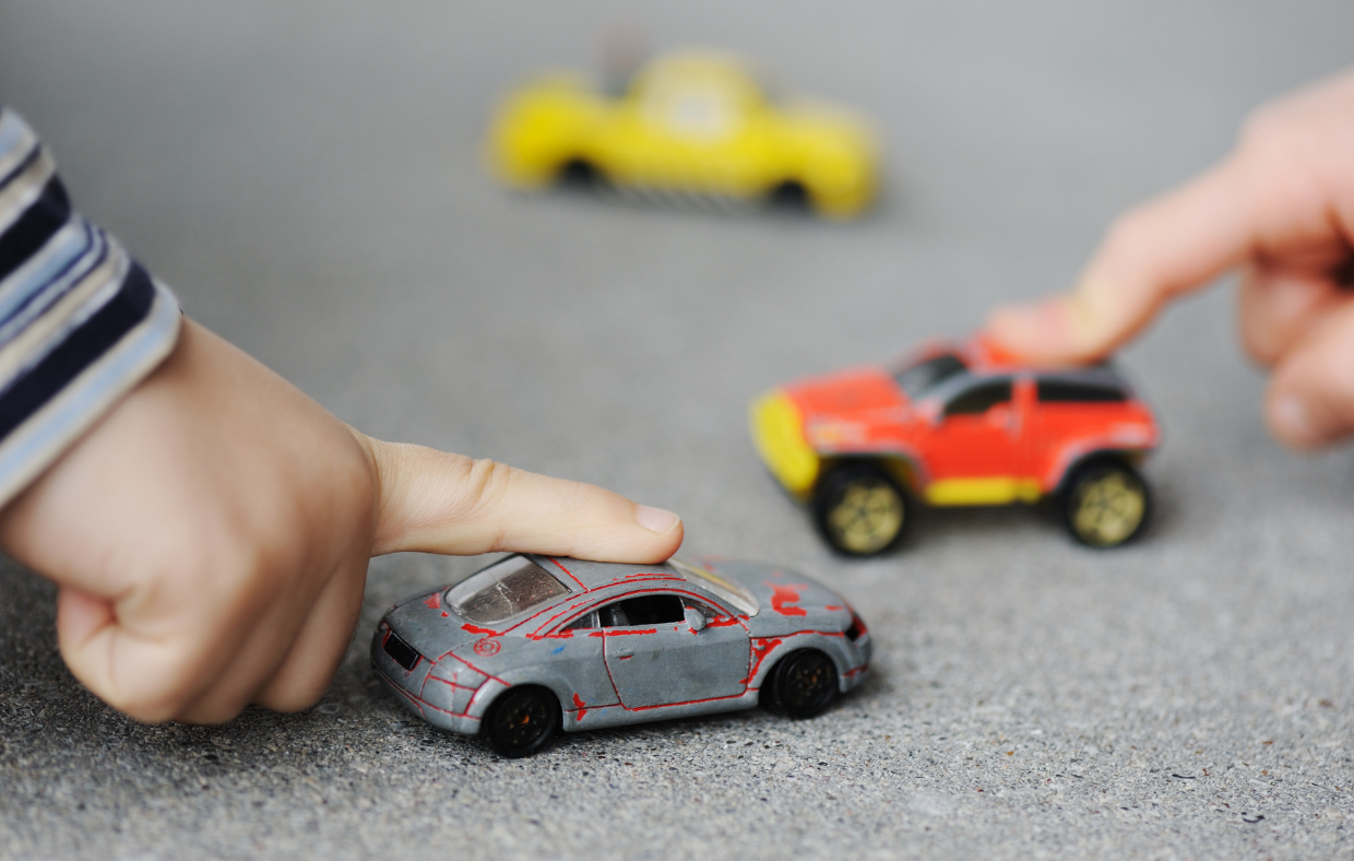 Photo of a child's hand playing with toy cars showing a source of lead exposure leading to lead poisoning.