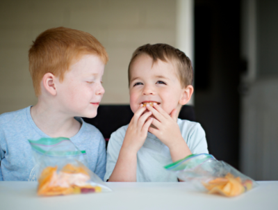 Two children eating food showing importance of health diets for childhood health.