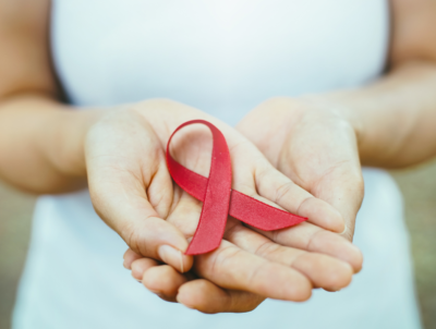 Photo of a person holding a red ribbon to promote local HIV testing.