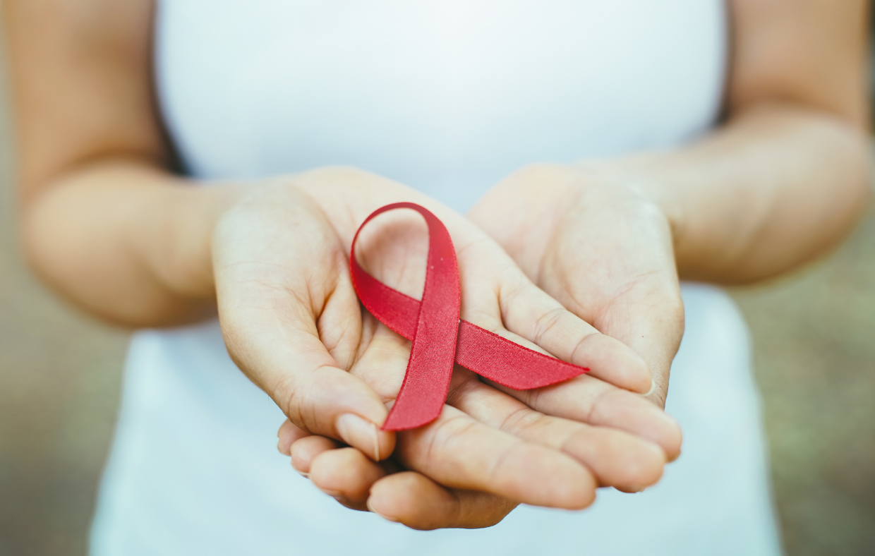 Photo of a person holding a red ribbon to promote local HIV testing.