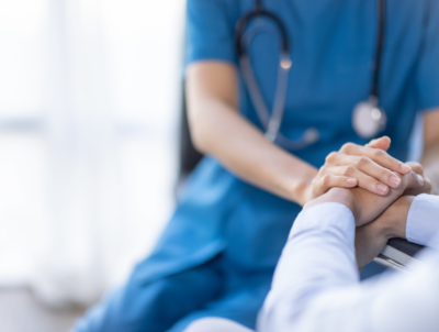 Photo of a provider holding a patient's hand showing importance of recruiting medical providers in rural areas.