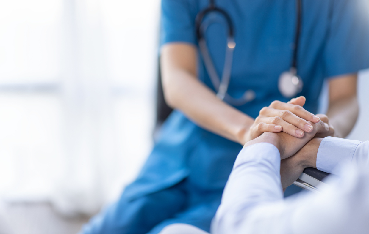 Photo of a provider holding a patient's hand showing importance of recruiting medical providers in rural areas.